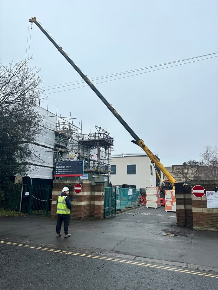 Mobile crane working over a scaffolded construction site