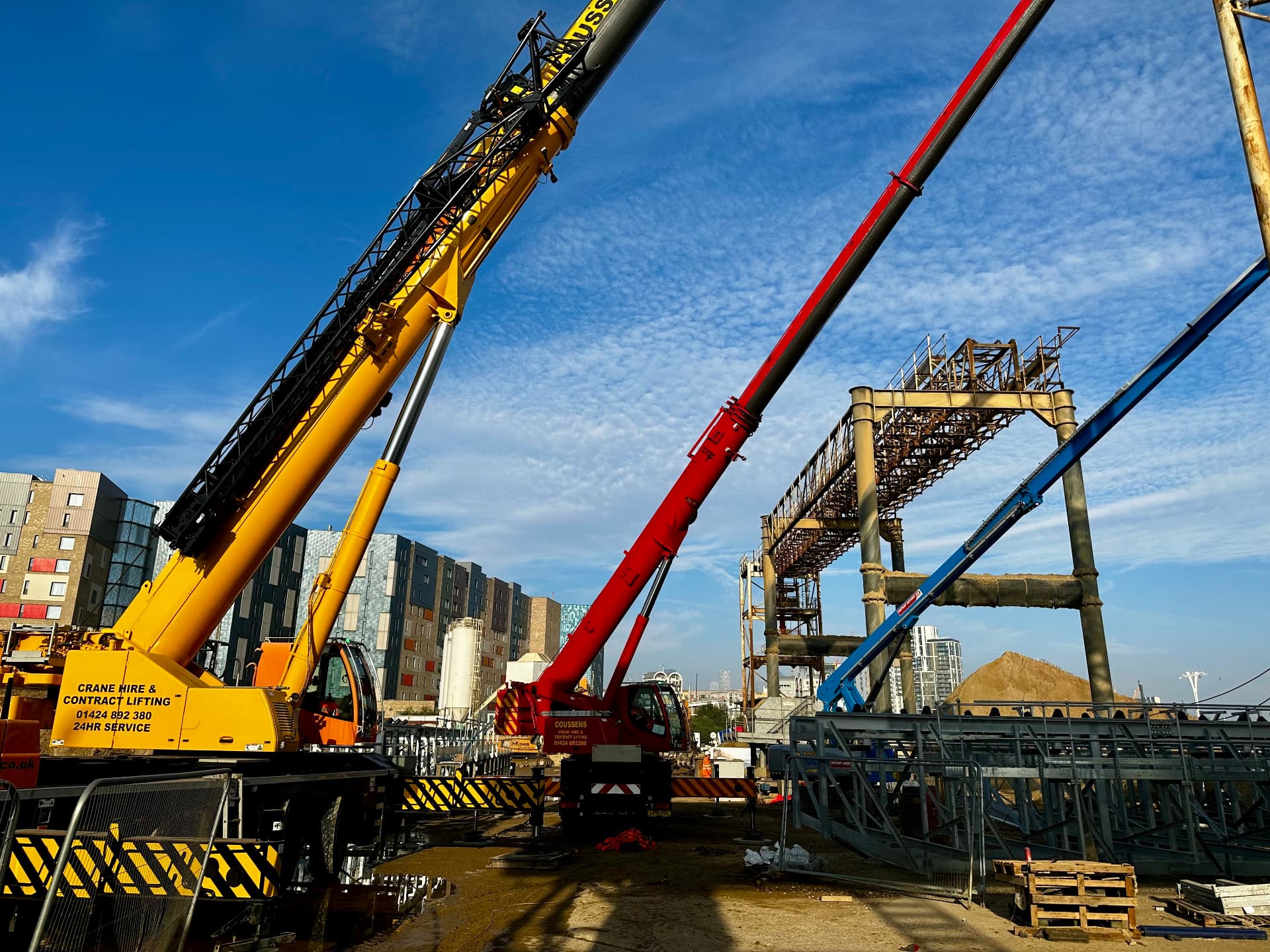 Multiple mobile cranes rigged together on a city construction site
